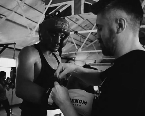 Boxing coach helping a boxer with gloves